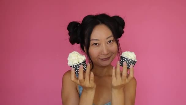 Funny Asian Girl Holds Cupcake Cream Pink Background — Vídeo de stock