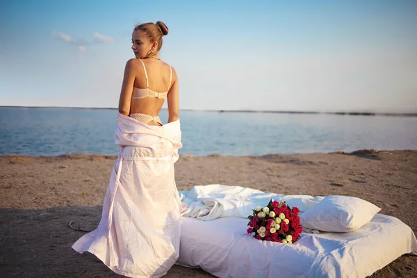日落时分 穿着女士内衣的性感金发女人在海滩上绽放花束 — 图库照片