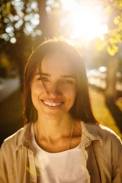 Outdoor atmospheric lifestyle photo of young beautiful lady at sunset. Brown hair and eyes. Warm autumn. Warm spring, the sun\'s rays from behind.