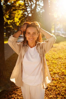 Gün batımında genç ve güzel bir bayanın açık havada çekilmiş bir fotoğrafı. Kahverengi saç ve gözler. Ilık sonbahar. Ilık bahar, güneş ışınları arkadan.