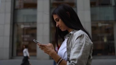 Tişört giyen, cep telefonu kullanan, cep telefonlu, cep telefonlu, cep telefonlu, cep telefonlu, cep telefonlu gülümseyen bir kadın.