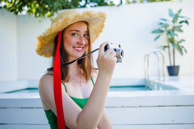 Güzel bir portre genç kızıl saçlı kadın rahatla açık havada yüzme havuzu, deniz kenarında tatil için okyanus kenarında gülümse.