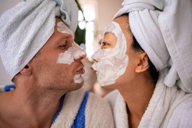 Karı koca kanepede uzanıyorlar ve maske portresini restore ediyorlar. Evde yardım kavramında sağlıklı yüz bakımı