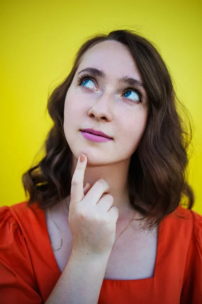 Let me think. Doubt concept. Doubtful pensive woman with thoughtful expression making choice. Young emotional woman. Human emotions, facial expression concept. Front . Studio. Isolated on yellow