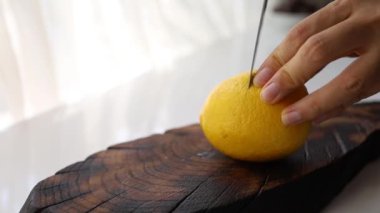 Şam bıçağı sulu limon keser. Meyve suyu kesme tahtasına akıyor. Sarı renk. 