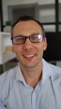 Genç iş adamının dikey görüntüsü akıllı telefonla yurt dışındaki iş ortaklarıyla ofisinde mutlu bir şekilde görüntülü sohbet ediyor.