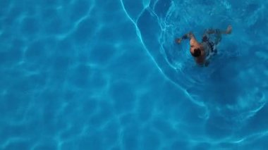 Havuzda mayo giymiş bir adamın yüzüşünü tepeden izle.
