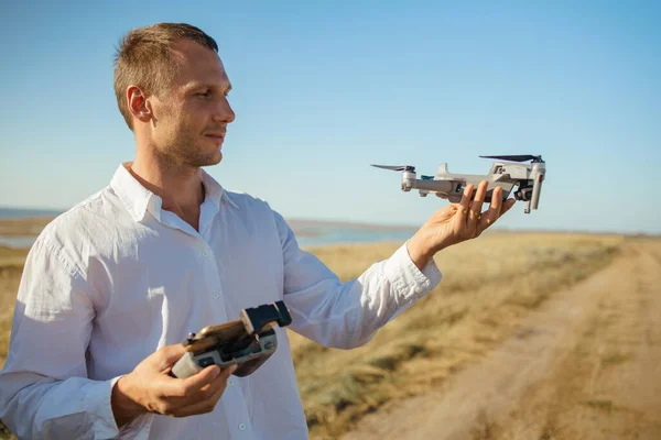 Man holding drone with remote controller in his hands. Guy taking aerial photos and videos
