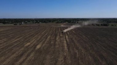 Gün batımında tarla traktörünün tarlaya püskürtücü, ot ilacı ve böcek ilacı sıktığı hava manzarası. Tarım makineleri yeşil alana böcek ilacı püskürtüyor, tarımsal doğal bahar işleri.