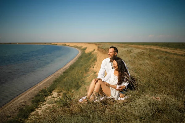 Schöne Gemischte Rasse Paar Sitzt Auf Einem Felsen Strand Und — Stockfoto