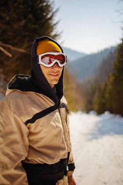 Kar ormanında kayak yapan genç adam tepenin üstünde duruyor..