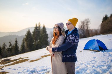 Mutlu çift Carpathian ormanının arka planında sarılıyor.