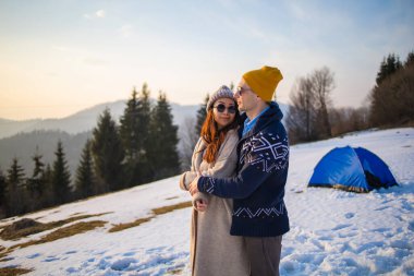 Mutlu çift Carpathian ormanının arka planında sarılıyor.