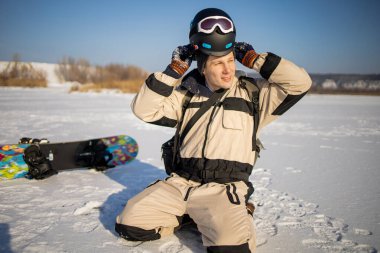 Kış ormanının arka planındaki bir dağda duran snowboard 'lu bir adam. Kış tatili aktivitesi. Sağlıklı bir yaşam tarzı. Ekstrem sporlar.