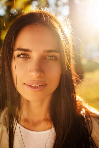 Doğanın tadını çıkaran güzel bir kadının portresi. Uzun saçlı, güzel bir sonbahar modeli. Gün batımında güneş ışığı. Sıcak tonlu sanat eserleri. 