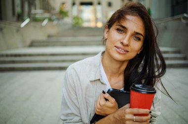 Neşeli, güzel, genç bir bayan güneş ışığında sabah kahvesini içiyor.