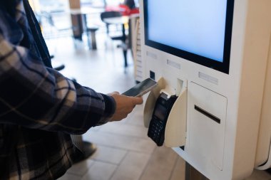 Yakın plan adam Counter elektronik ödeme süpermarket akıllı telefon erkek el satın aldı cep telefonu ile dükkanlarda satın almak için ödeme Contacless NFC Terminal Kapalı Kart okuyucu.