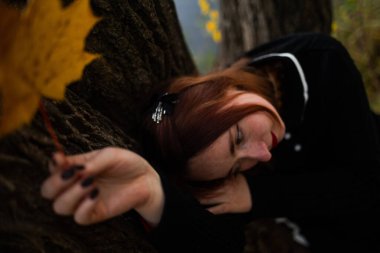 Gizemli bir sonbahar ormanında, ağacın altında oturan siyahlı bir kadın..