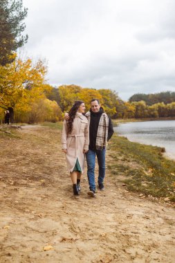 Genç aşık bir çift sonbahar parkında yürüyor. Romantik randevu.