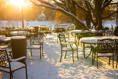 Bahçedeki kış kafesi. Masalar ve banklar karla kaplı..