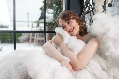 Beyaz bulutlu genç bir kadın. Sarışın kadın, melek gibi temiz ciltli ve makyajlı stüdyoda poz veriyor..