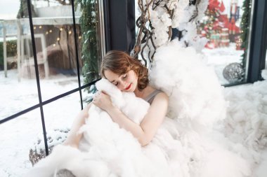 Beyaz bulutlu genç bir kadın. Sarışın kadın, melek gibi temiz ciltli ve makyajlı stüdyoda poz veriyor..