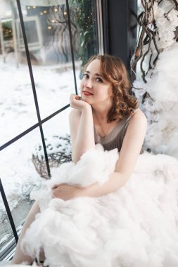 Beyaz bulutlu genç bir kadın. Sarışın kadın, melek gibi temiz ciltli ve makyajlı stüdyoda poz veriyor..