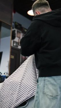 Genç bir erkek berber erkek bir müşterinin saçını düzeltir. Profesyonel saç bakım ürünleri. Bir berberin sinematik yakın çekimi erkek müşteriye soluk saç tıraşı yapıyor. Kısa kırpıcı saç stilinin yavaş çekim görüntüsü.