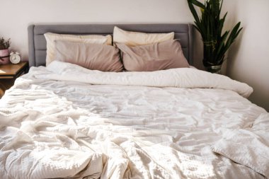 Beyaz çarşaflı ve yastıklı bir yatağın yakın çekimi. Uykudan sonra düzeltilip düzeltilmiş. Görüntü bir huzur ve sükunet hissi uyandırıyor..