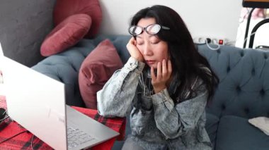 Yorgun ve serbest çalışan Asyalı kadın geç saatlere kadar mutfakta çalışıyor. Dizüstü bilgisayara bakarken uykulu ve yorgun hissediyorum. Yorgunlukla mücadele ediyor ve son teslim tarihinden önce işini bitirmeye çalışıyor..