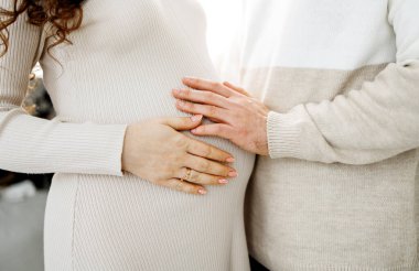 Hamile bir kadın ve kocasının göbeğine dokunurken çekilmiş görüntüsü, yakın plan..