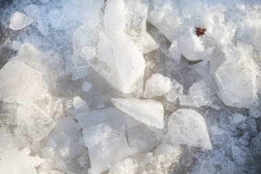 Donmuş bir yüzeyde kışın gün ışığıyla aydınlatılan yarı saydam buz parçalarının yakın çekimi. Üst görünüm.