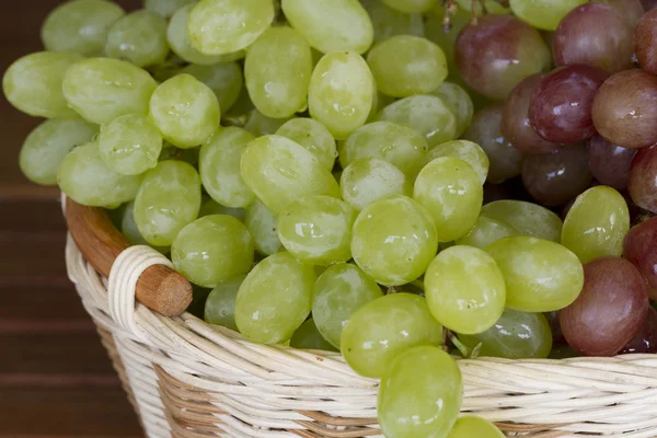 Gröna och röda druvor i flätade korgen. — Stockfoto