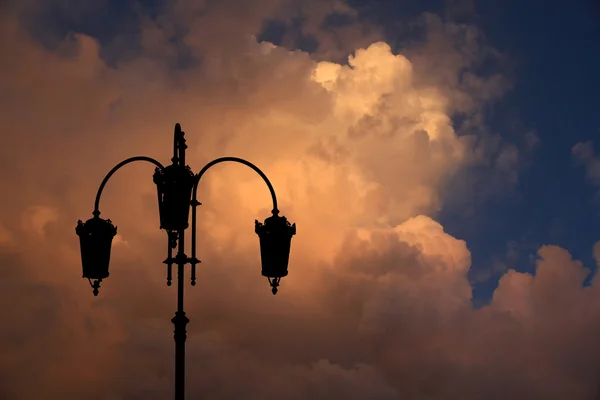 Silhueta de lâmpada de rua preta contra fundo brilhante multi colorido por do sol nuvens no céu . — Fotografia de Stock