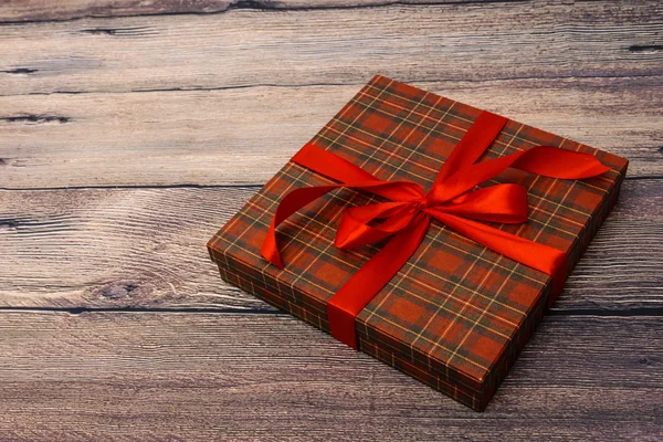 Small gift box with red ribbon on wooden table — Stock Photo, Image