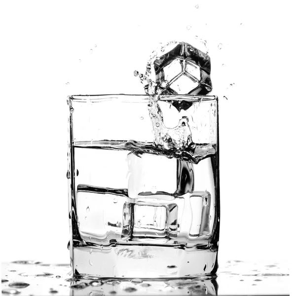 Cubo de hielo salpicando en un vaso de agua fría — Foto de Stock