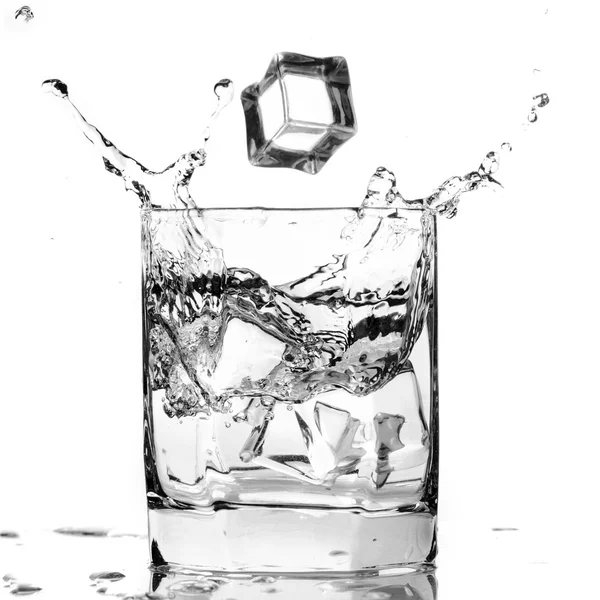 Ледяной куб брызгает в прохладный стакан воды — стоковое фото