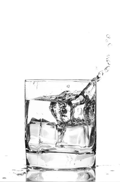 Ice cube splashing in a cool glass of water — Zdjęcie stockowe