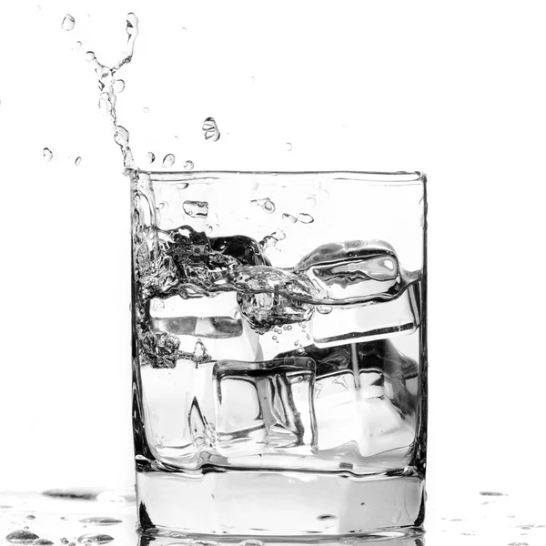 Ice cube splashing in a cool glass of water — Zdjęcie stockowe