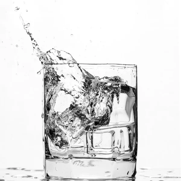 Ijsblokje spetteren in een koele glas water — Stockfoto