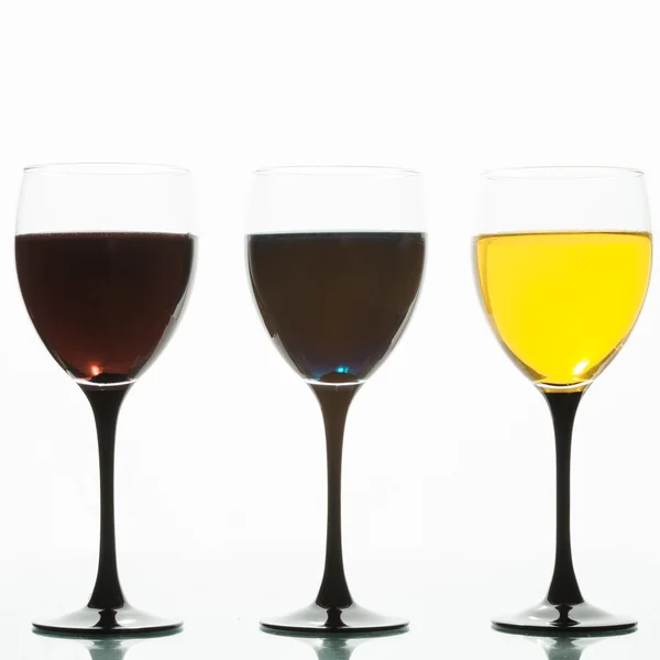 Drei Weingläser mit farbigen Flüssigkeiten auf weißem Hintergrund — Stockfoto