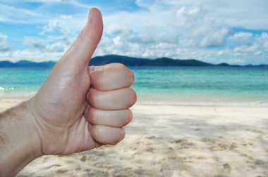 closeup başparmak yukarıya üstünde plaj arka plan mavi gökyüzü