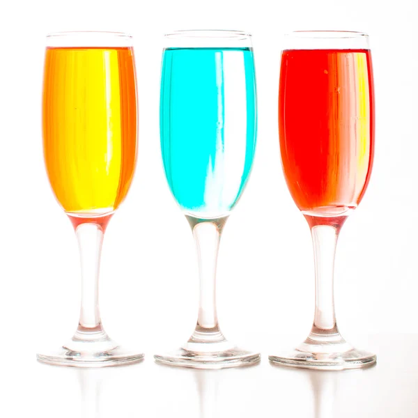 Келихи шампанського з кольоровими рідинами, що стоять підряд — стокове фото