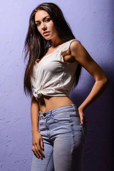 Sexy chica morena bronceada en un chaleco blanco y jeans — Foto de Stock