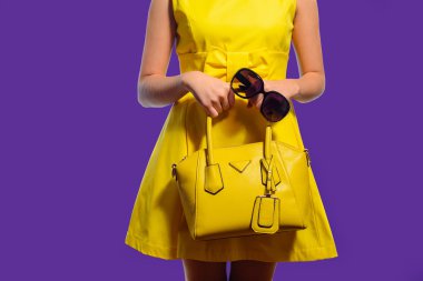 El çantası ve güneş gözlüğü ile sarı elbiseli şık moda kadın