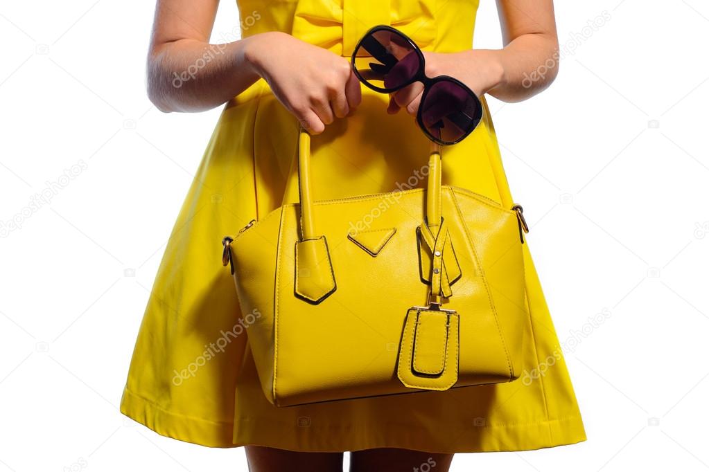 Elegant fashionable woman in yellow dress with handbag and sunglasses