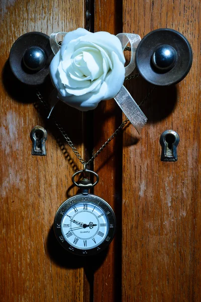 Reloj de bolsillo colgando en la manija del gabinete con flor de rosa blanca —  Fotos de Stock