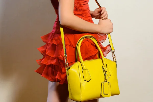 黄色のハンドバッグで赤いドレスを着たファッショナブルな若い女性 ストック写真