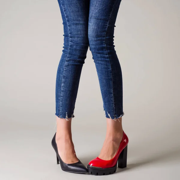 Woman legs in summer shoes isolated over neutral background. select your pair concept - red or black shoes