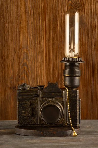 a lamp made of an old film camera on a wooden background